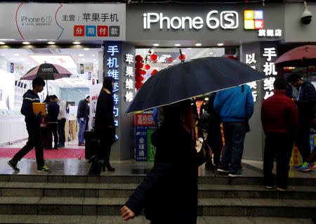 People walk past stores promoting the Apple iPhone 6S in the southern city of Shenzhen, China January 26, 2016. REUTERS/Bobby Yip/File Photo