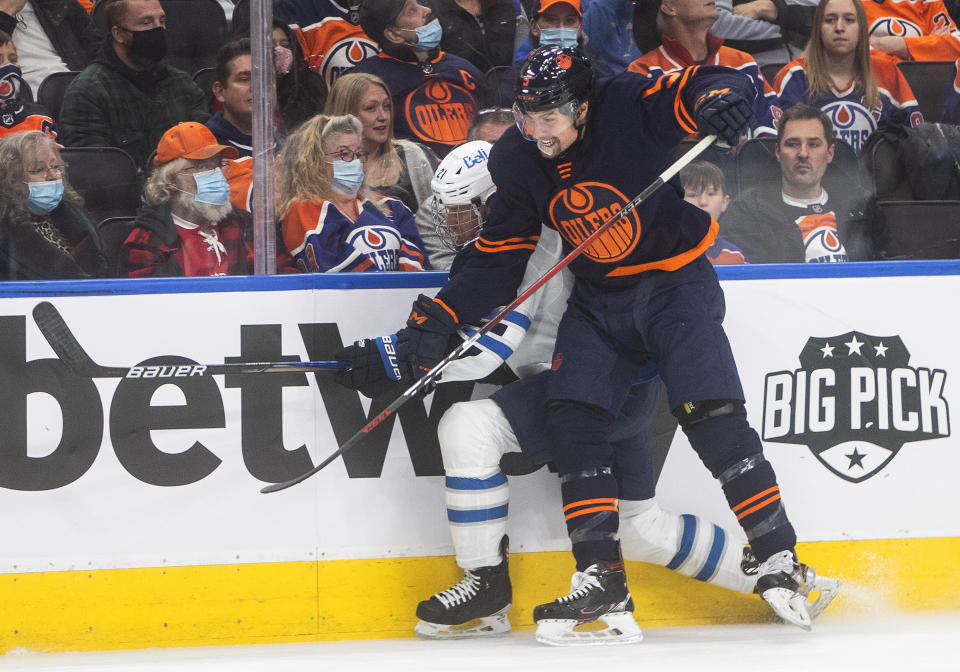 Winnipeg Jets' Dominic Toninato (21) is checked by Edmonton Oilers' Cody Ceci (5) during first period NHL hockey action in Edmonton, Alberta, on Thursday, Nov. 18, 2021. (Jason Franson/The Canadian Press via AP)