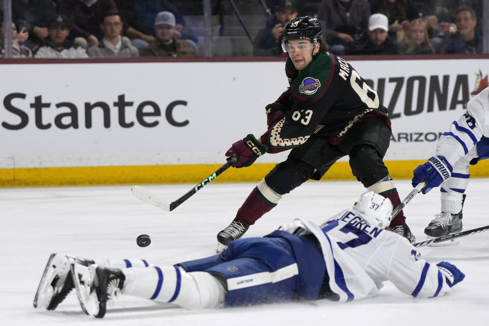 Arizona Coyotes left wing Matias Maccelli (63) shoots over Toronto Maple Leafs defenseman Timothy Liljegren during the first period of an NHL hockey game Wednesday, Feb. 21, 2024, in Tempe, Ariz. (AP Photo/Rick Scuteri)