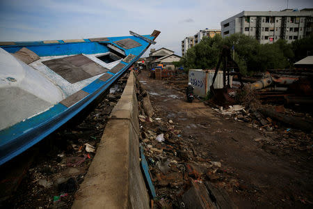 A wooden boat lies stranded on a concrete sea wall at Muara Baru fishing port in Jakarta, Indonesia, December 5, 2017. REUTERS/Beawiharta