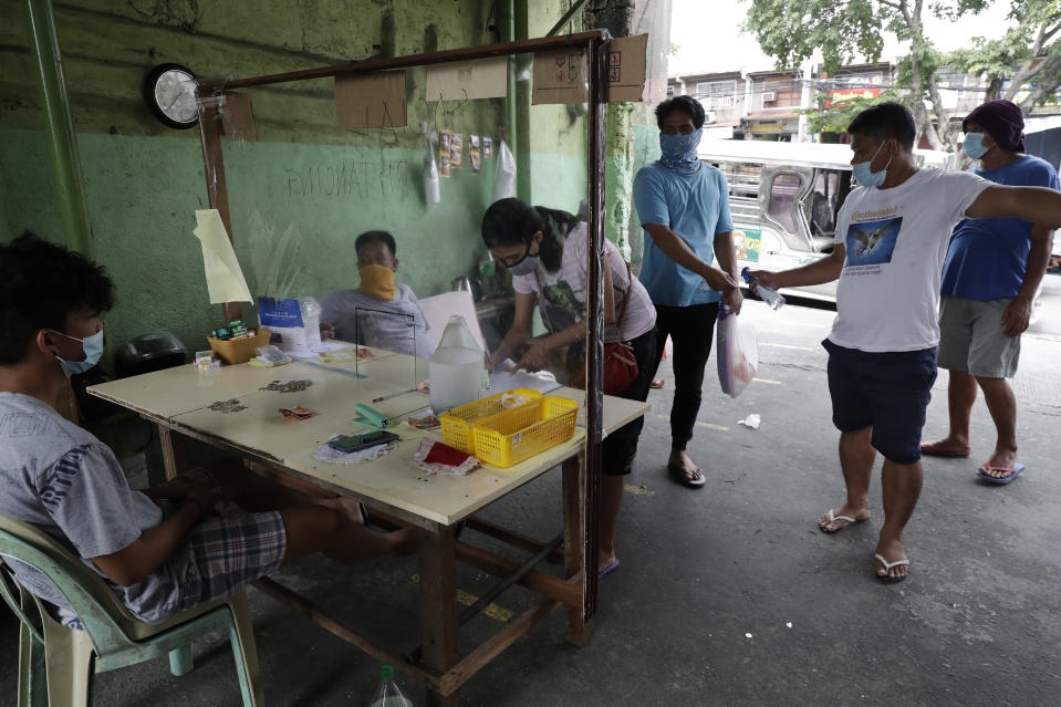 Passengers write their names and contact numbers before boarding a passenger jeepney to help contact tracing in trying to curb the spread of the COVID19, Sunday, Aug. 2, 2020, in Quezon city, Philippines. Coronavirus infections in the Philippines continues to surge Sunday as medical groups declared the country was waging a losing battle against the contagion and asked the president to reimpose a lockdown in the capital. (AP Photo/Aaron Favila)