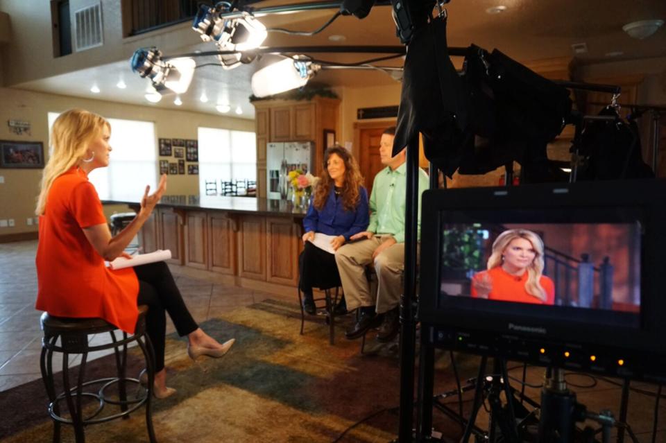 Megyn Kelly sits on a bench in a red dress and interviews Michelle and Jim Bob Duggar.