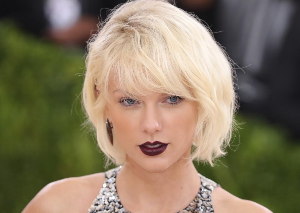 Taylor Swift at an event wearing a metallic dress with a sleek, short hairstyle
