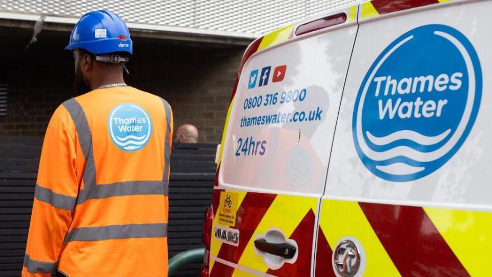 Man in Thames Water hi-viz jacket standing next to a Thames Water van