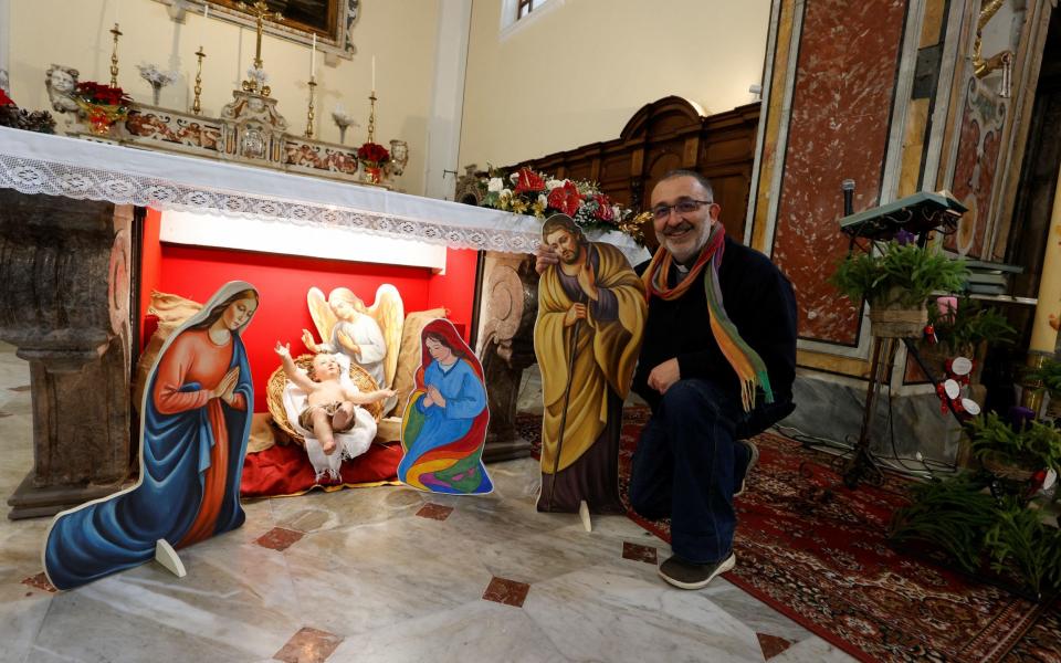 Vitaliano Della Sala, the parish priest, poses for a photo in front of the nativity scene