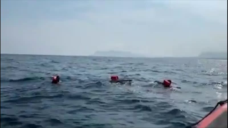 Migrants swim away from Spanish rescue ship Open Arms after more than 70 of them jumped from the ship to attempt to reach the coast, at sea near Palermo