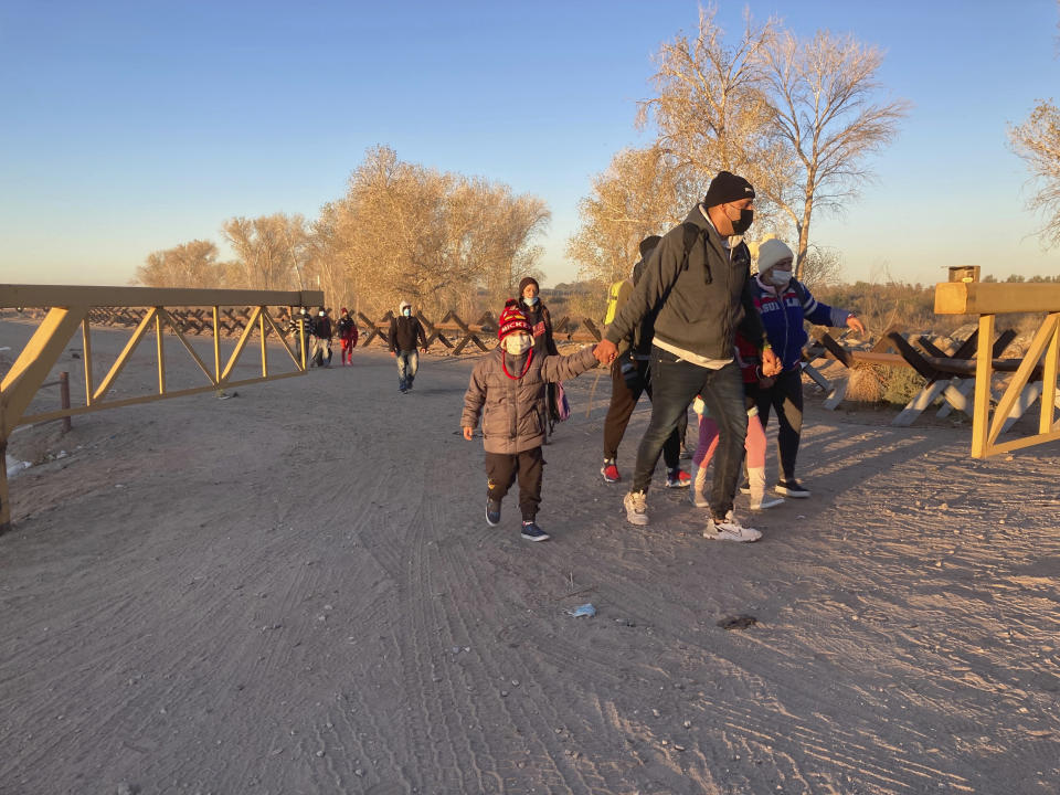 FILE - Migrants walk to an area in Yuma, Ariz., Sunday, Feb. 6, 2022, where they surrender to Border Patrol agents, hoping to remain in the United States to seek asylum. A federal appeals court has upheld sweeping asylum restrictions to prevent spread of COVID-19 but restored protections to prevent migrant families from being expelled to their home countries without a chance to plead their cases. (AP Photo/Elliot Spagat, File)