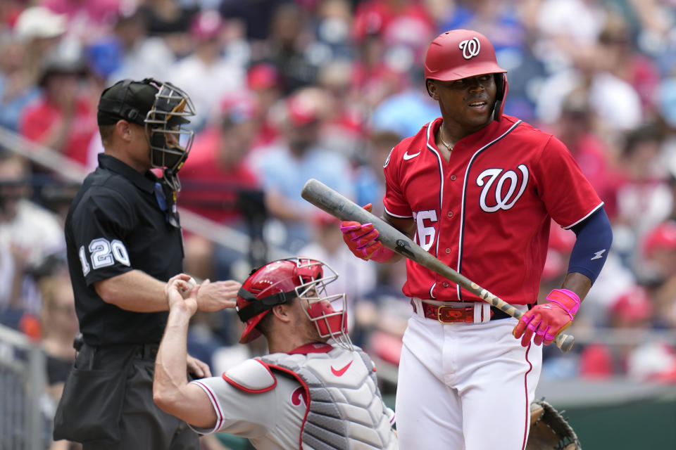 Washington Nationals' Stone Garrett, right, walks off the field after striking out swinging in front of Philadelphia Phillies catcher J.T. Realmuto and umpire Brian Walsh in the second inning of a baseball game, Sunday, June 4, 2023, in Washington. (AP Photo/Patrick Semansky)