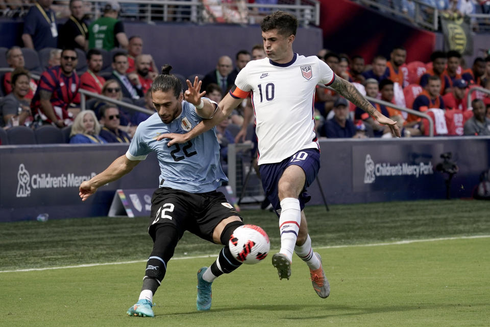 Uruguay defender Martin Caceres (4) and USA forward Christian Pulisic (10) chase the ball during the first half of an international friendly soccer match Sunday, June 5, 2022, in Kansas City, Kan. (AP Photo/Charlie Riedel)