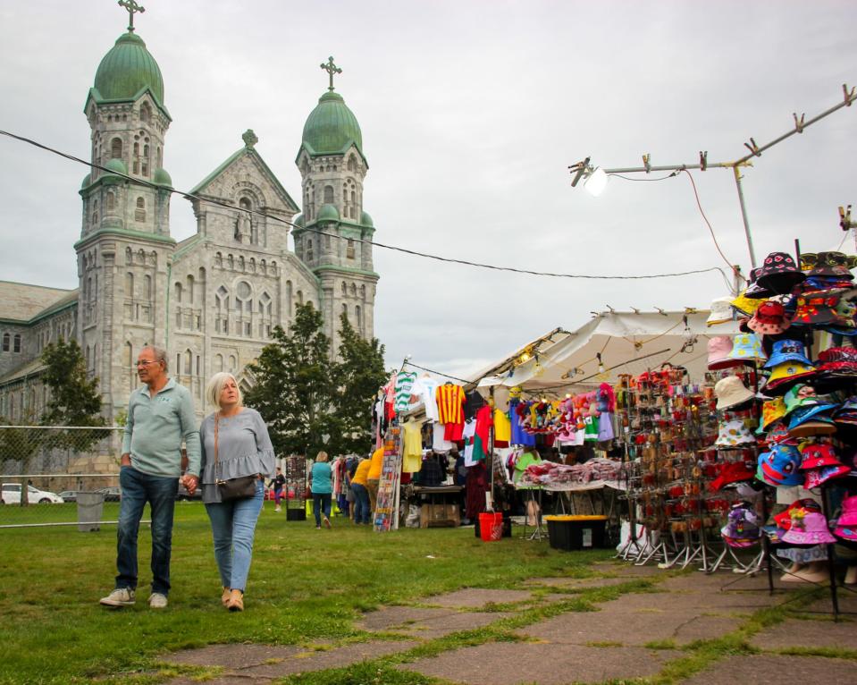 A couple strolls past the merchandise booths at the Great Feast of the Holy Ghost of New England on Thursday, Aug. 24, in Fall River.