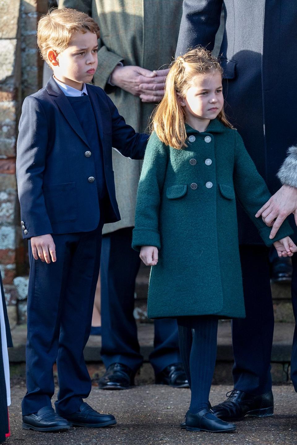 Charlotte wore a dark green coat by Amaia, which coordinated with mom Kate’s green hat and green suede pumps (Kate also wore a long gray coat with a faux fur collar by Catherine Walker & Co). 