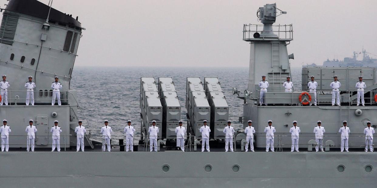 Chinese soliders stand in a line on a warship