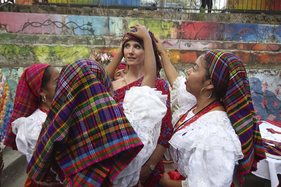 Jennifer Siebel Newsom, wife of California Gov. Gavin Newsom, receives help from dance students, to place on her head a traditional Panchimalco shawl worn by women in the last century, during a visit to Panchimalco, the home of indigenous Salvadorans, El Salvador, Monday, April 8, 2019. (AP Photo/Salvador Melendez)
