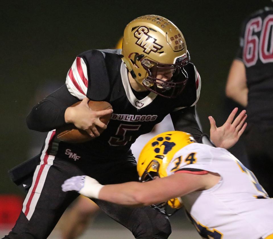Stow quarterback Nate Boozer, top, is brought down short of the first down marker by St. Ignatius linebacker Christopher Aerni during the first half of a Division I playoff football game, Friday, Nov. 5, 2021, in Stow, Ohio. [Jeff Lange/Beacon Journal]