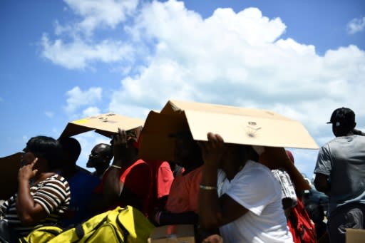 People seek shelter from the sun as they await evacuation at a dock in Marsh Harbour, Bahamas, on September 7, 2019, in the aftermath of Hurricane Dorian