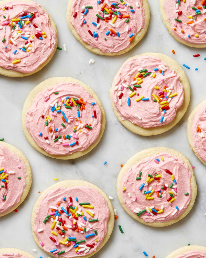 Overhead shot of lofthouse cookies on a white marble surface, with rainbow sprinkles laying around them.