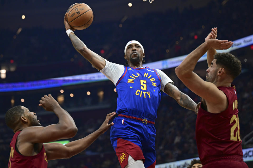 Denver Nuggets guard Kentavious Caldwell-Pope goes to the basket against Cleveland Cavaliers forward Georges Niang, right, and center Tristan Thompson in the first half of an NBA basketball game, Sunday, Nov. 19, 2023, in Cleveland. (AP Photo/David Dermer)