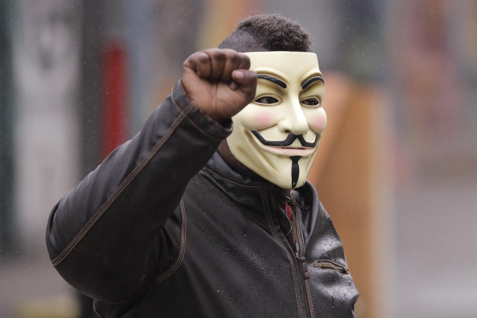 A protester raises his fist as he wears a Guy Fawkes mask near the Seattle Police Department East Precinct building, Tuesday, June 30, 2020 at the CHOP (Capitol Hill Occupied Protest) zone in Seattle. Earlier Tuesday, Seattle Department of Transportation workers removed barricades at the intersection of 10th Ave. and Pine St., but protesters quickly moved couches, trash cans and other materials in to replace them. The area has been occupied by protesters since Seattle Police pulled back from their East Precinct building following violent clashes with demonstrators earlier in the month. (AP Photo/Ted S. Warren)