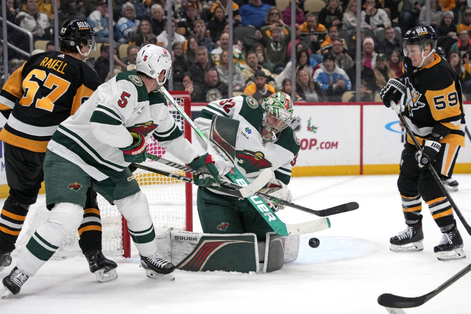 Pittsburgh Penguins' Rickard Rakell (67) can't get his stick on a rebound off Minnesota Wild goaltender Filip Gustavsson (32) with Jake Middleton (5) defending during the second period of an NHL hockey game in Pittsburgh, Monday, Dec. 18, 2023. (AP Photo/Gene J. Puskar)