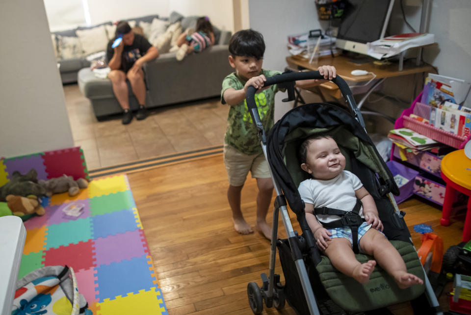 Stefano Lopez, 5, pushes his brother Adonai, 8-months, on a stroller as their mother, Venezuelan asylum-seeker Oriana Marcano, checks her phone in El Paso, Texas, Friday, May 12, 2023. When the family was lost in Panama's Darien Gap last year, her husband, Luis Lopez, often knelt in the mud to beg God not to abandon them. (AP Photo/Andres Leighton)