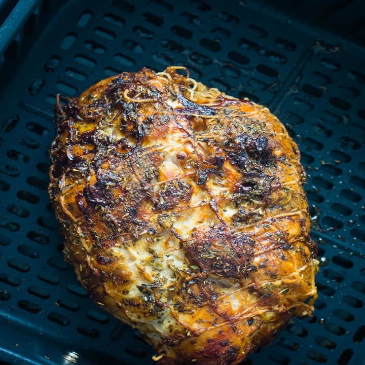 A turkey breast in the basket of an air fryer.