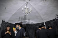 Ultra-Orthodox Jewish men, some wearing face masks, inspect an etrog, a citrus fruit, to determine if it is ritually acceptable as one of the four items used as a symbol on the Jewish holiday of Sukkot, during the current nationwide lockdown due to the coronavirus pandemic in the Orthodox Jewish neighborhood of Mea Shearim in Jerusalem, Wednesday Sept. 30, 2020. The holiday commemorates the Israelites 40 years of wandering in the desert and a decorated hut is erected outside religious households as a sign of temporary shelter. The weeklong holiday begins on Friday. (AP Photo/Oded Balilty)