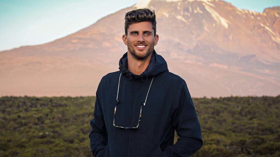 Barrett Pall stands in front of a mountain.