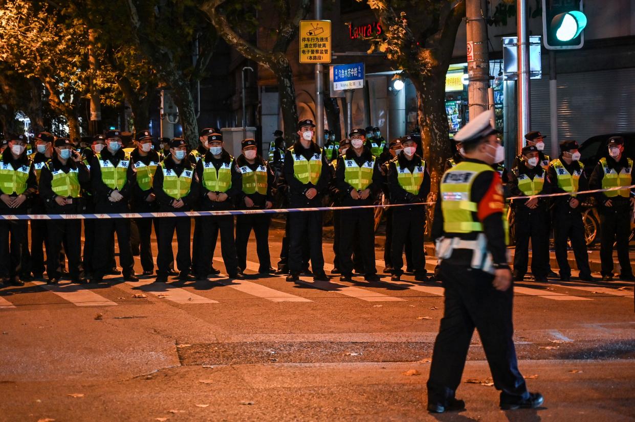 Police officers block Wulumuqi street, named for Urumqi in Mandarin, in Shanghai on November 27, 2022, in the area where protests against China's zero-Covid policy took place the night before following a deadly fire in Urumqi, the capital of the Xinjiang region. (Photo by Hector RETAMAL / AFP) (Photo by HECTOR RETAMAL/AFP via Getty Images)