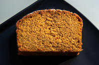 A freshly baked loaf of bread on a black plate, shown in a close-up side view