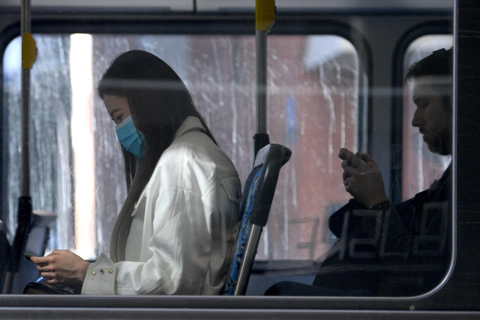 Two commuters on a Sydney bus, one wearing a face mask.