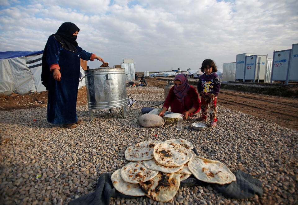 A displaced woman makes bread at Hassan Sham camp in Iraq
