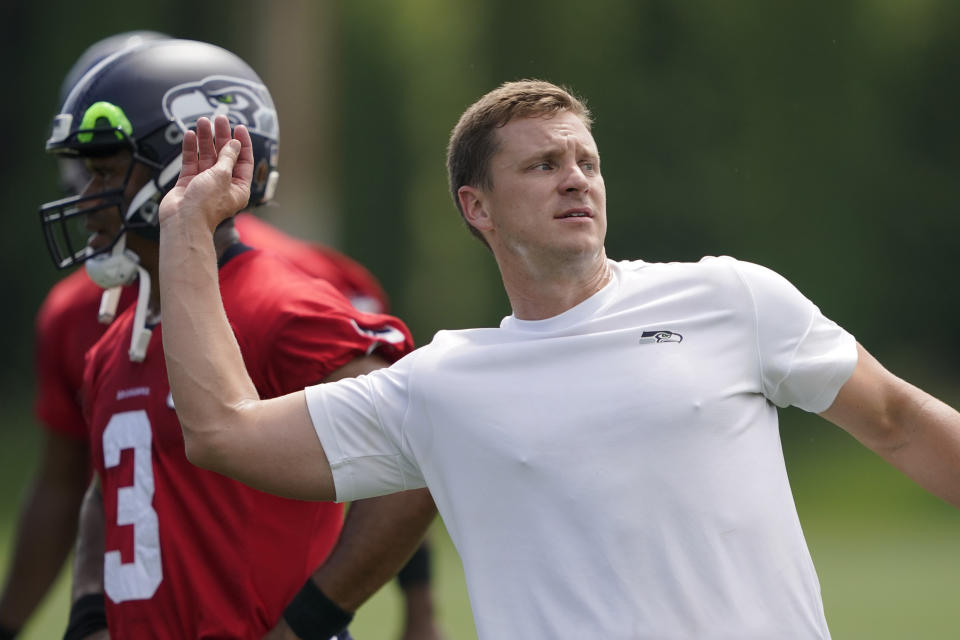 Seattle Seahawks quarterbacks coach Austin Davis makes a throwing motion as he works with Seahawks quarterback Russell Wilson, left, during NFL football practice on July 28, 2021, in Renton, Wash. Auburn has hired Davis as offensive coordinator, head coach Bryan Harsin announced Saturday, Dec. 18, 2021. (AP Photo/Ted S. Warren)