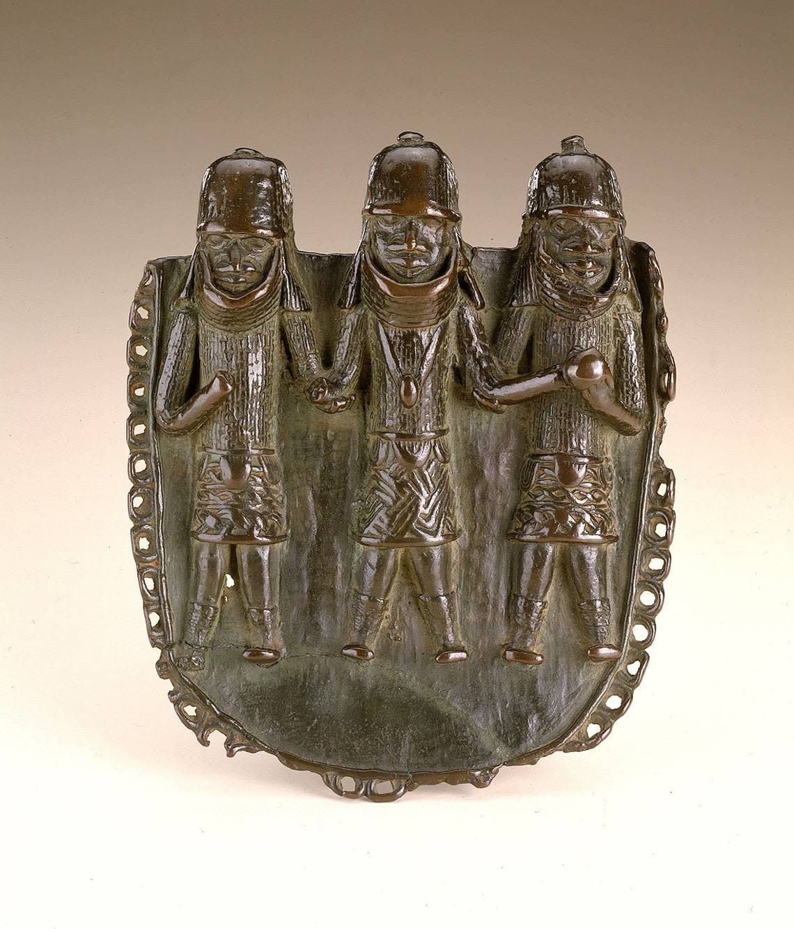 Copper pendant with three figures, the oba (king) in the center and attendants on either side.
