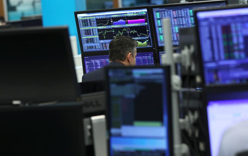 A trader works as screens show market data at CMC markets in London