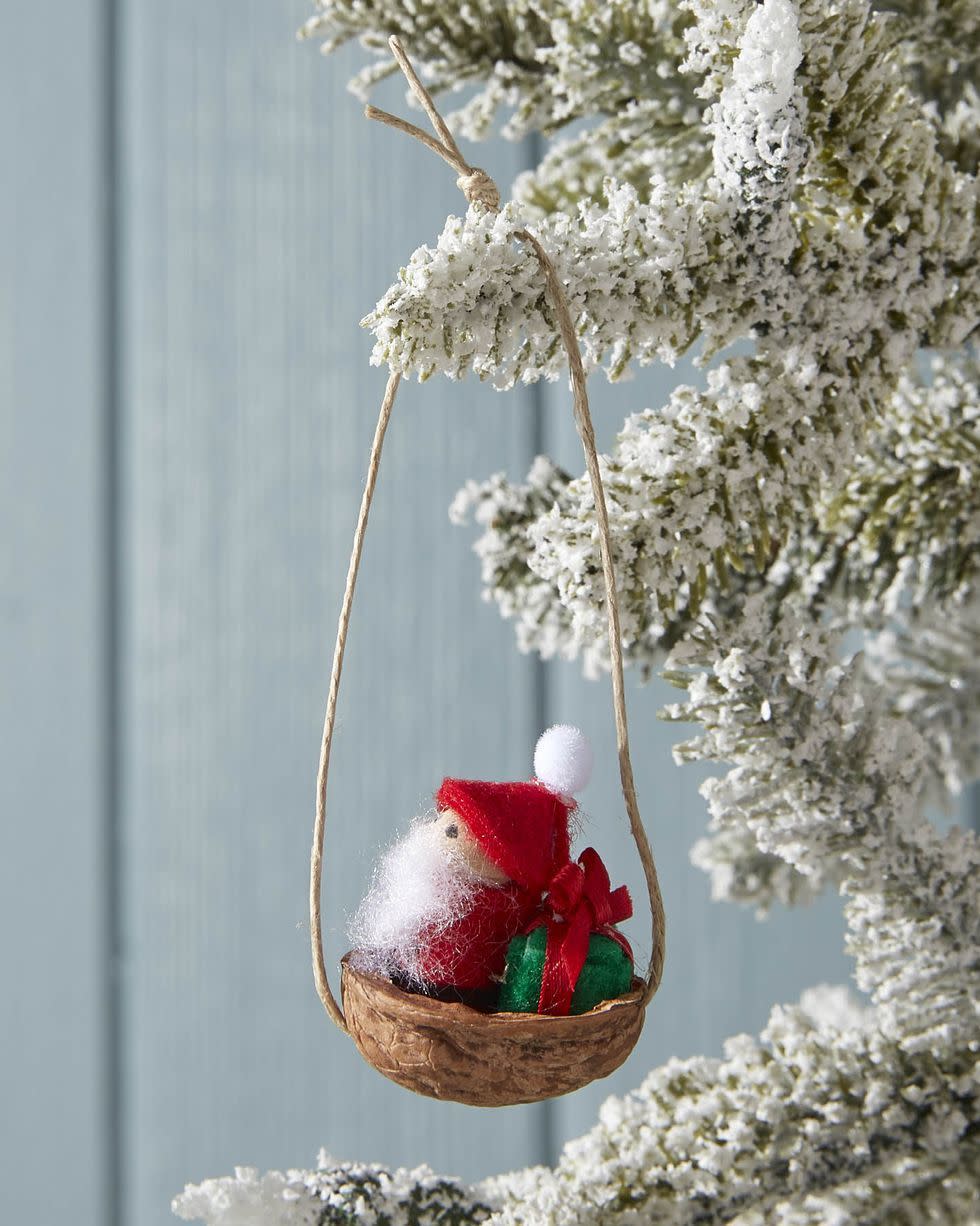 small ornament hanging on a flocked tree made out of a walnut for santa's sleigh