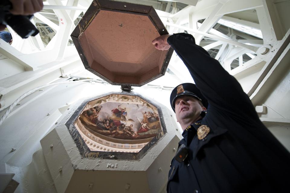 U.S. Capitol Police Officer Adam Taylor holds open one of the coffer windows in the ceiling of the U.S. Capitol dome during a media tour on Capitol Hill in Washington, December 19, 2013. Americans longing for a makeover in Washington will get their wish partially granted as the dome of the U.S. Capitol - but not the lawmakers who work inside - undergoes a facelift. The dome of the capitol building will be undergoing a restoration project to halt deterioration of the dome's cast iron as well as ensure the protection of the interior of the dome and rotunda. (REUTERS/Douglas Graham/POOL)