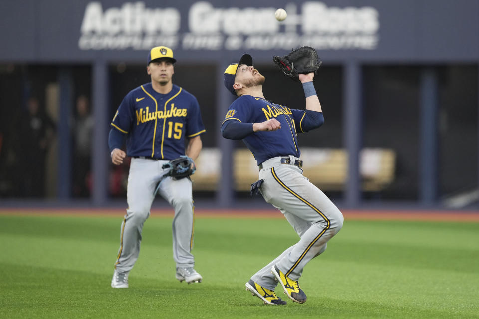 Milwaukee Brewers' Mike Brosseau, right, catches a fly ball hit by Toronto Blue Jays' Vladimir Guerrero Jr., while shortstop Tyrone Taylor (15) watches during the fourth inning of a baseball game Tuesday, May 30, 2023, in Toronto. (Nathan Denette/The Canadian Press via AP)