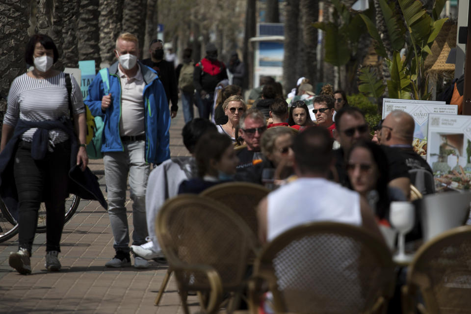 Tourists sit on a terrace next to the sea at the Spanish Balearic Island of Mallorca, Spain, Saturday, March 27, 2021. Efforts in Spain to restart tourism activity is drawing a mixed picture due to a patchwork of national, regional and European rules on travel that is confusing both tourists and their hosts. (AP Photo/Francisco Ubilla)