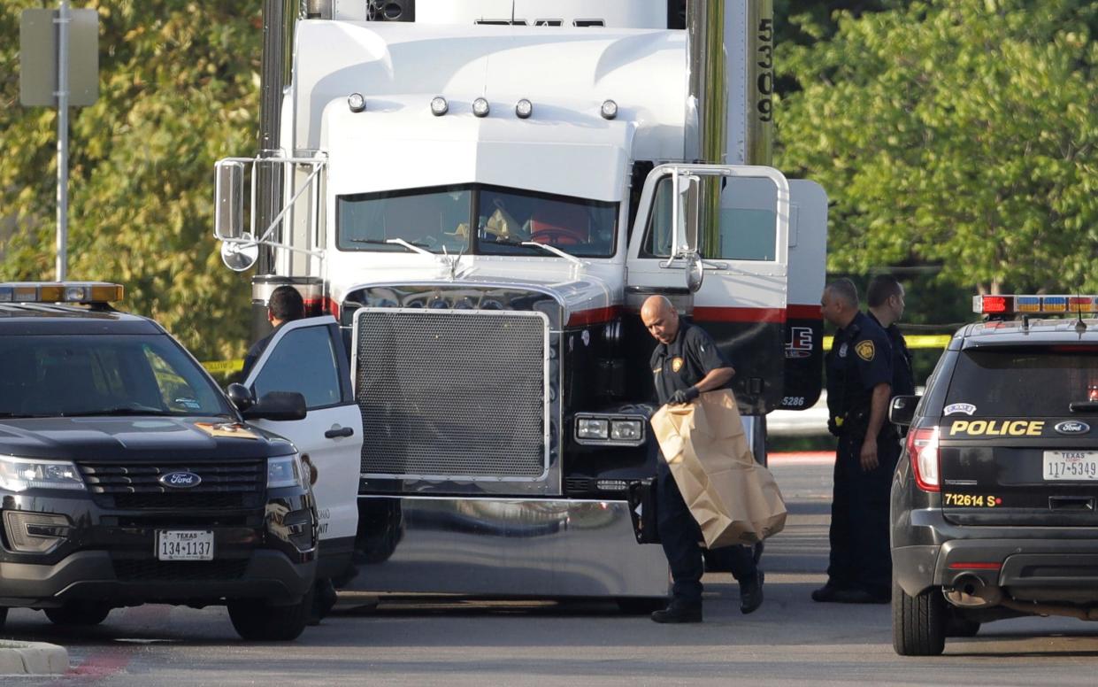 San Antonio police officers investigate the scene where eight people were found dead in a tractor-trailer loaded with at least 30 others outside a Walmart store  - Copyright 2017 The Associated Press. All rights reserved.