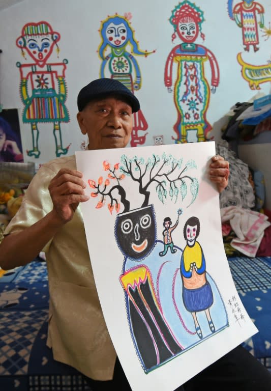 93-year-old artist Huang Yung-fu poses with some of his artwork in the Rainbow Village in Taichung, central Taiwan