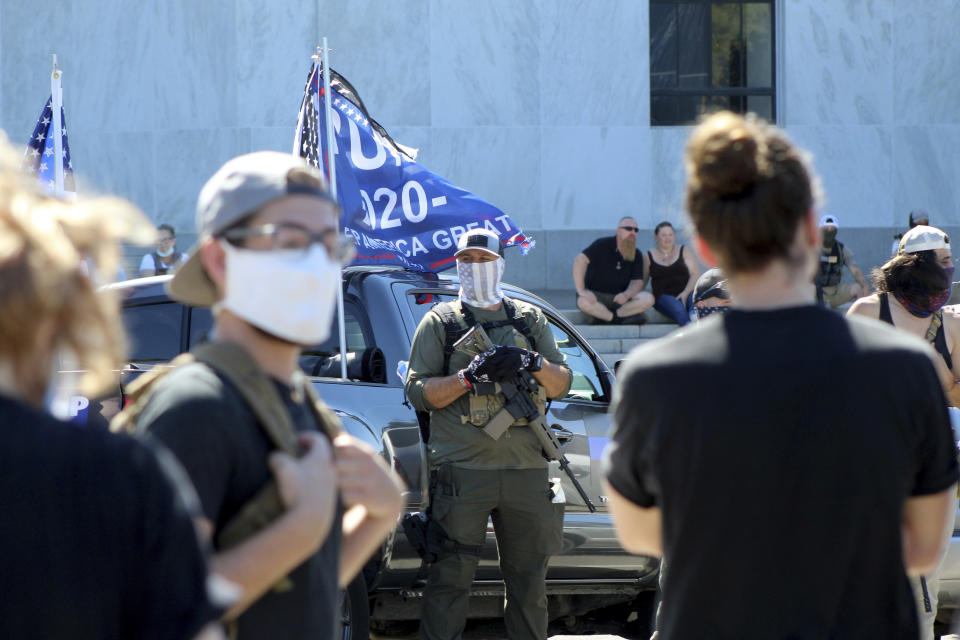 A right-wing protester armed with an AR-15 style rifle looks at Black Lives Matter counter-protesters who are across the street in front of the Oregon State Capitol in Salem, Ore., on Monday, Sept. 7, 2020. Hundreds of people gathered on Labor Day in a small town south of Portland for a pro-President Donald Trump vehicle rally, just over a week after member of a far-right group was fatally shot after a Trump caravan went through Oregon's largest city. (AP Photo/Andrew Selsky)