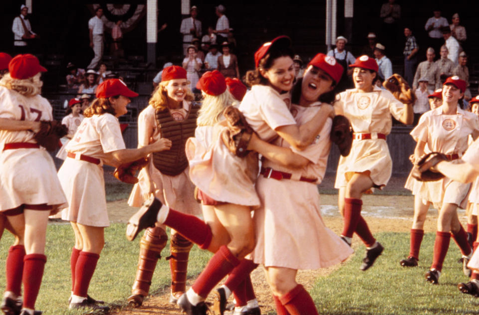 Women baseball players celebrating on the field, with Madonna and Rosie O'Donnell hugging