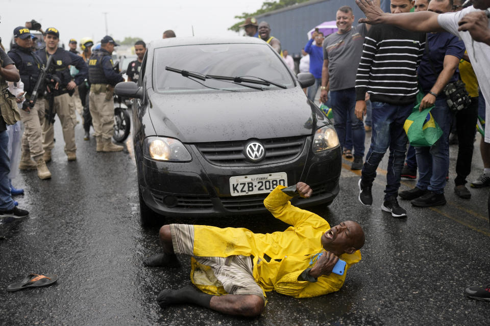 A supporter of President-elect Luiz Inacio Lula da Silva slips on a rain soaked pavement as he continues to chant slogans surrounded by truckers loyal to outgoing President Jair Bolsonaro blocking a highway, in Itaborai, Rio de Janerio state, Brazil, Tuesday, Nov. 1, 2022. Truckers supportive of Bolsonaro blocked hundreds of roads early Tuesday to protest his election loss to Lula da Silva. (AP Photo/Silvia Izquierdo)