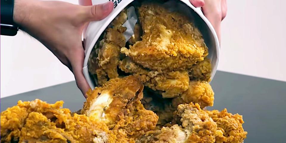 A bucket of KFC fried chicken poured onto a plate.