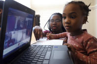FILE - In this Feb. 10, 2021, file photo, Lear Preston, 4, who attends Scott Joplin Elementary School, participates in her virtual classes as her mother, Brittany Preston, background, assists at their residence in Chicago's South Side. Amid mounting tensions about reopening schools, the Centers for Disease Control and Prevention planned to release long-awaited guidance Friday, Feb. 12, on what measures are needed to get children back into the classroom during the pandemic. (AP Photo/Shafkat Anowar, File)
