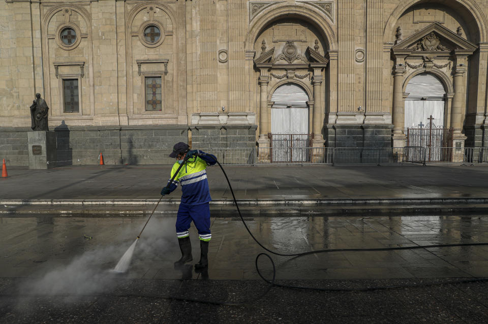 Un trabajador de la ciudad lava una calle que pasa por la Catedral Metropolitana en la Plaza de Armas en Santiago, Chile, el jueves 25 de marzo de 2021. Las autoridades anunciaron el restablecimiento de una cuarentena en toda la ciudad para ayudar a contener la propagación del COVID-19. (AP Foto/Esteban Felix)