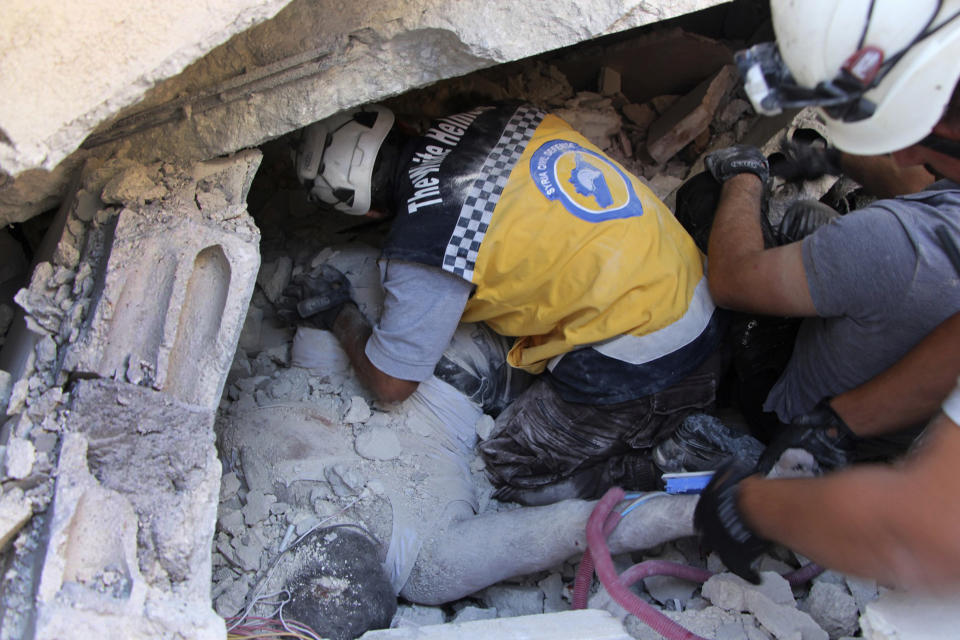 This photo provided by the Syrian Civil Defense White Helmets, which has been authenticated based on its contents and other AP reporting, shows Syrian White Helmet civil defense workers remove a body from the rubble at the scene of an explosion that brought down a five-story building, in the village of Sarmada, near the Turkish border, north Syria, Sunday, Aug. 12, 2018. Syrian opposition activists say the explosion killed several people and wounded many others. The cause of the blast wasn't immediately known. (Syrian Civil Defense White Helmets via AP)