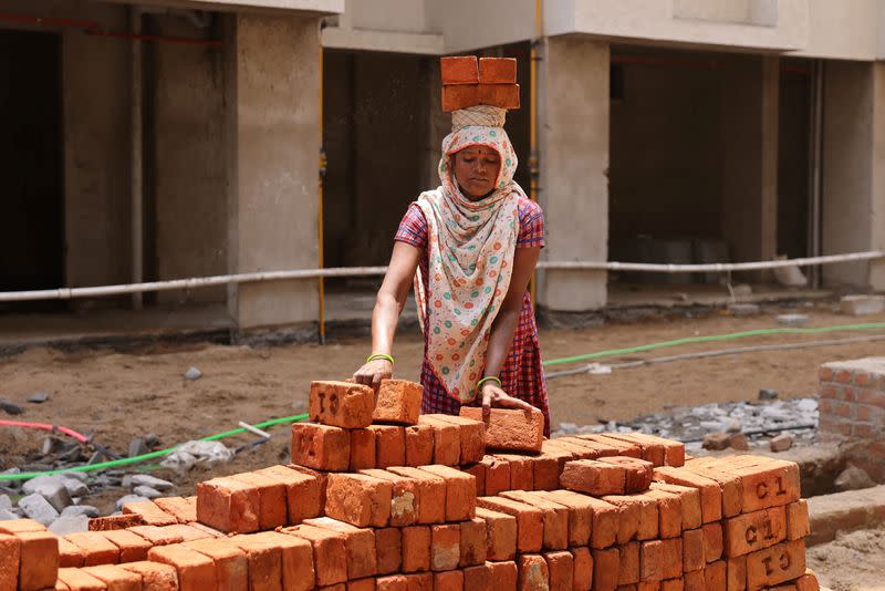 FILE PHOTO: A woman carries bricks at a construction site in Ahmedabad