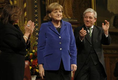 German Chancellor Angela Merkel is applauded by Speaker of the House of Commons John Bercow (R) and Frances D'Souza (L) after her speech to members of both Houses of Parliament in the Royal Gallery of the Palace of Westminster in London February 27, 2014. REUTERS/Luke Macgregor