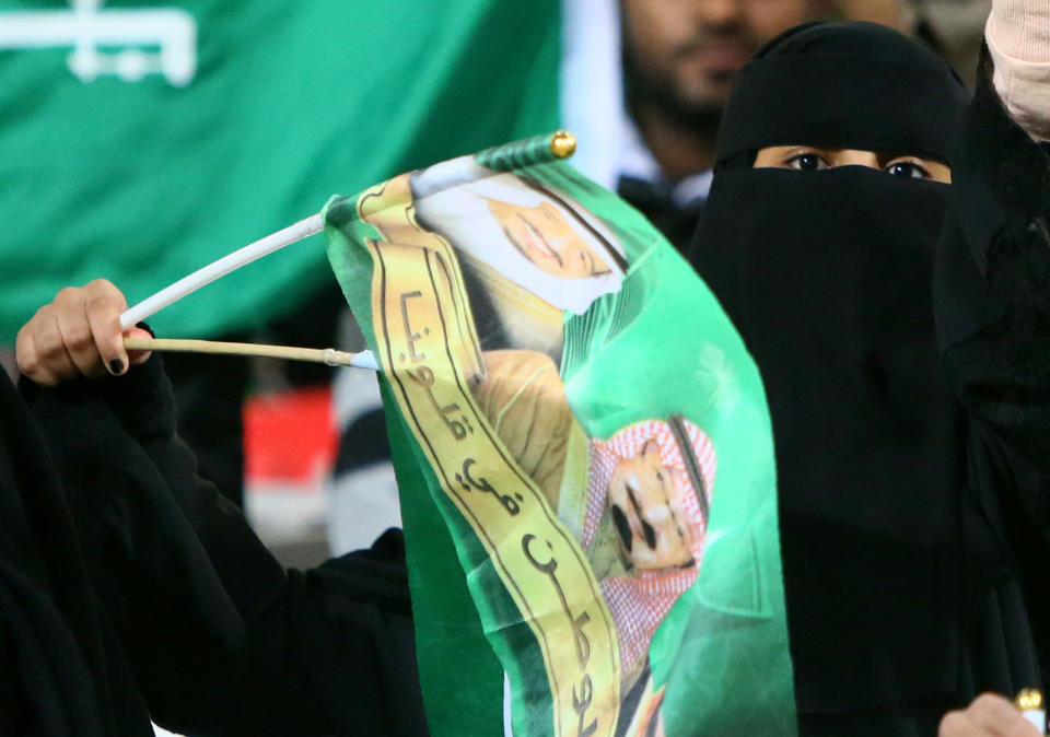 Official reports suggest women will be allowed to attend soccer matches in a new stadium in 2014. The women will be segregated from the men in sections for families.  <em>A Saudi fully veiled woman waves a flag with the picture of Saudi King Abdullah prior the start of Saudi Arabia match against Kuwait in the 21st Gulf Cup in Manama, on January 12, 2013. (MARWAN NAAMANI/AFP/Getty Images)</em>
